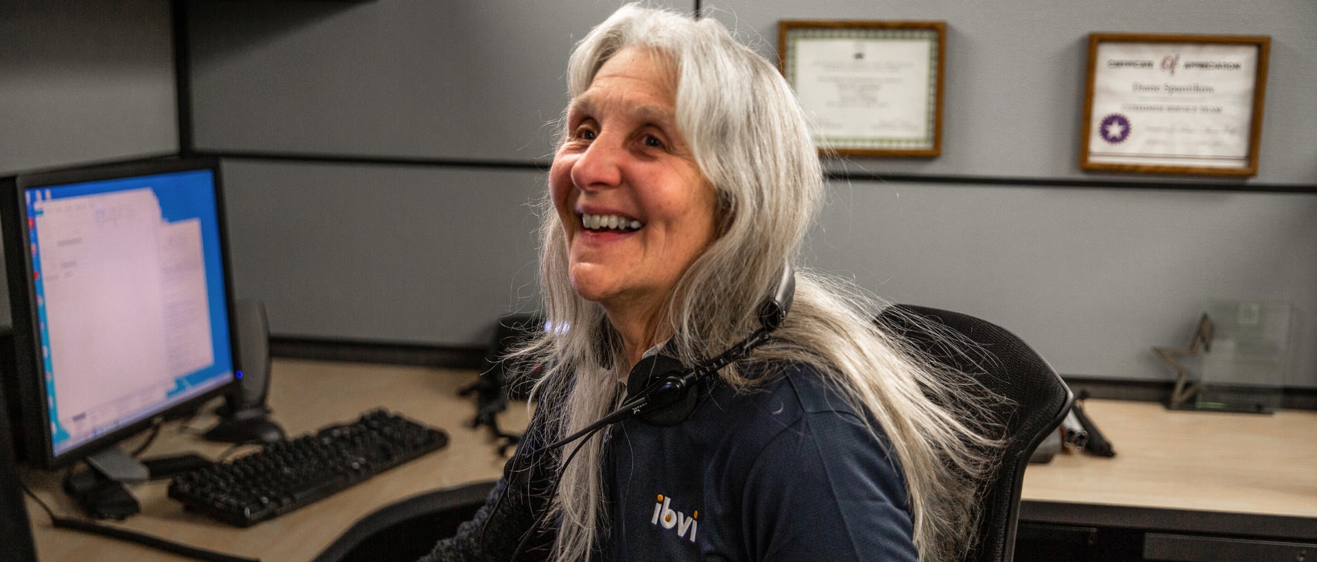 Diane S. of IBVI smiles at the camera while working on a computer
