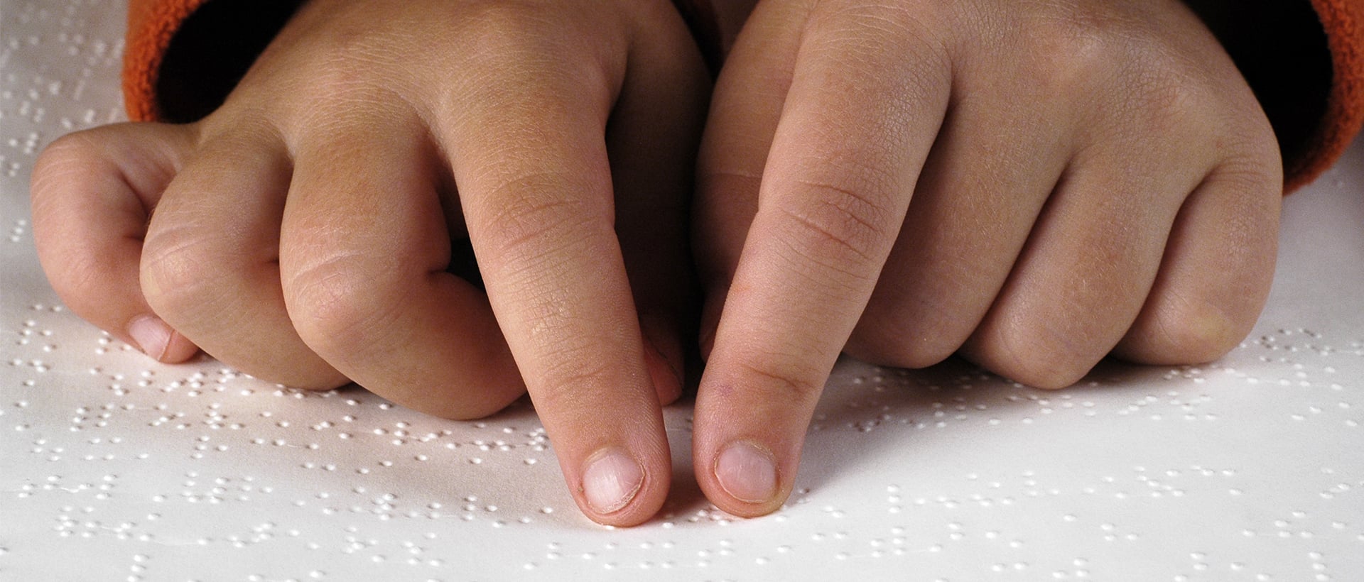 a child's hands reading braille