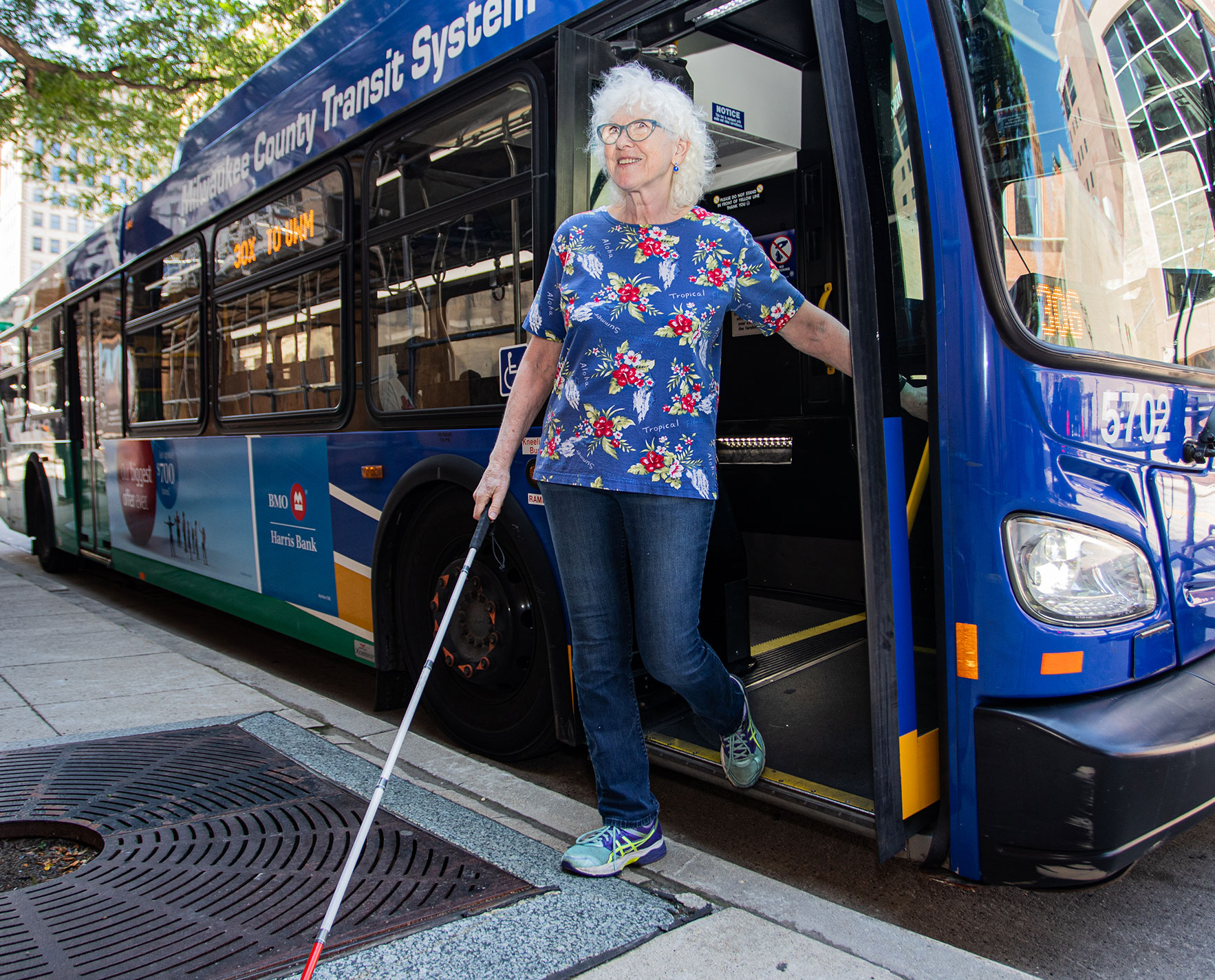 Woman getting off of a city bus with a cane