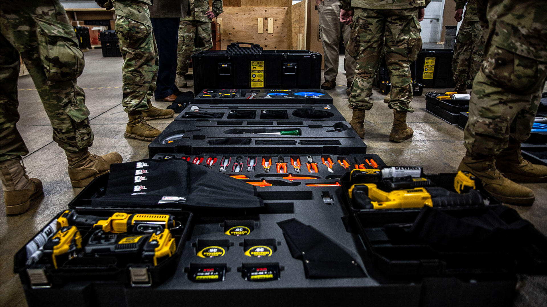 people in military camo standing around open tool kits