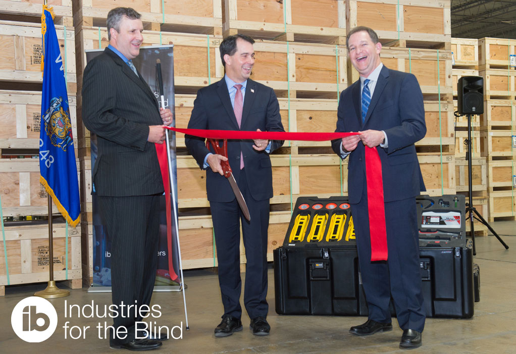 Three men leading a ribbon cutting in a warehouse