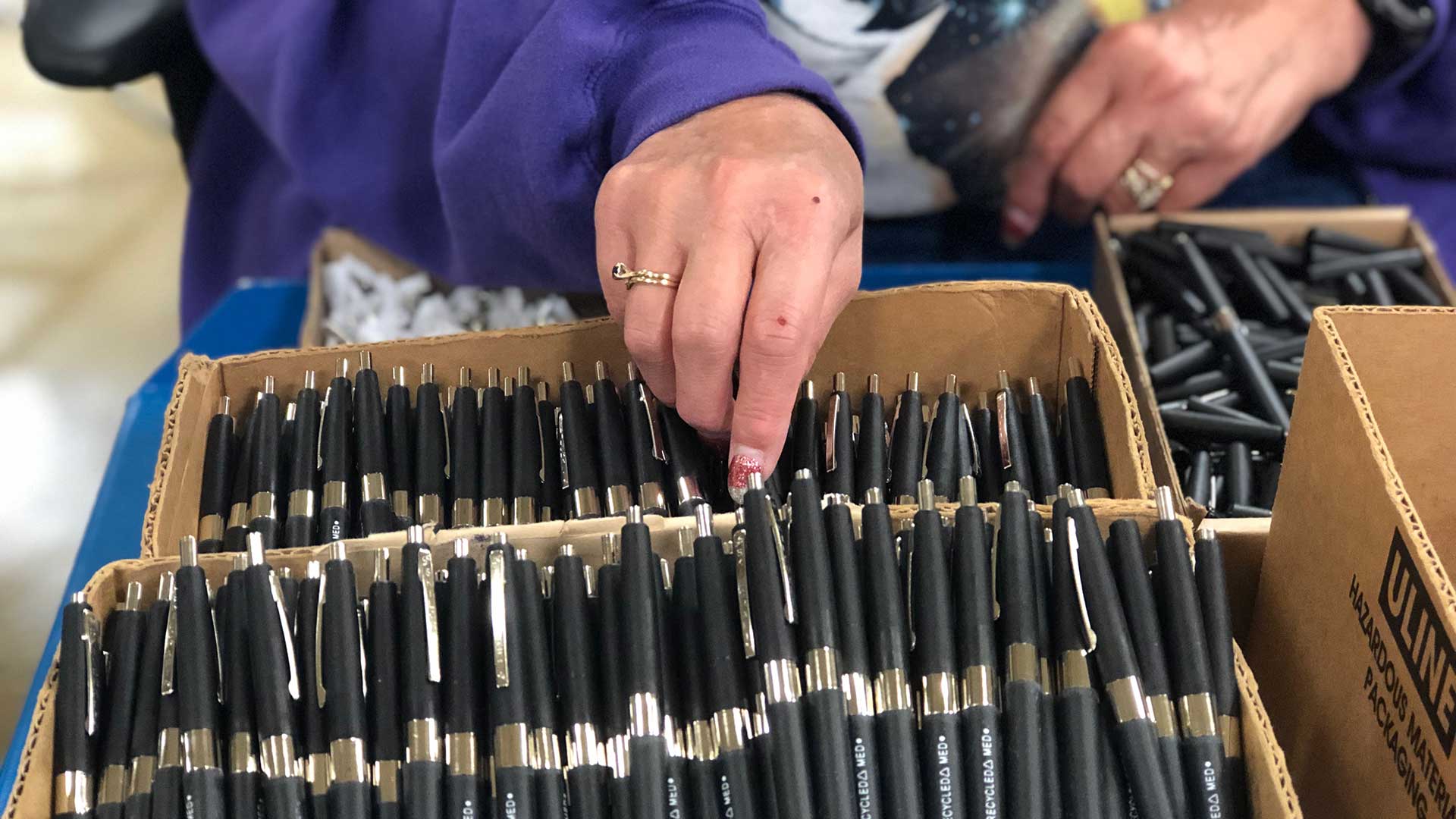 Person organizing pens in a box