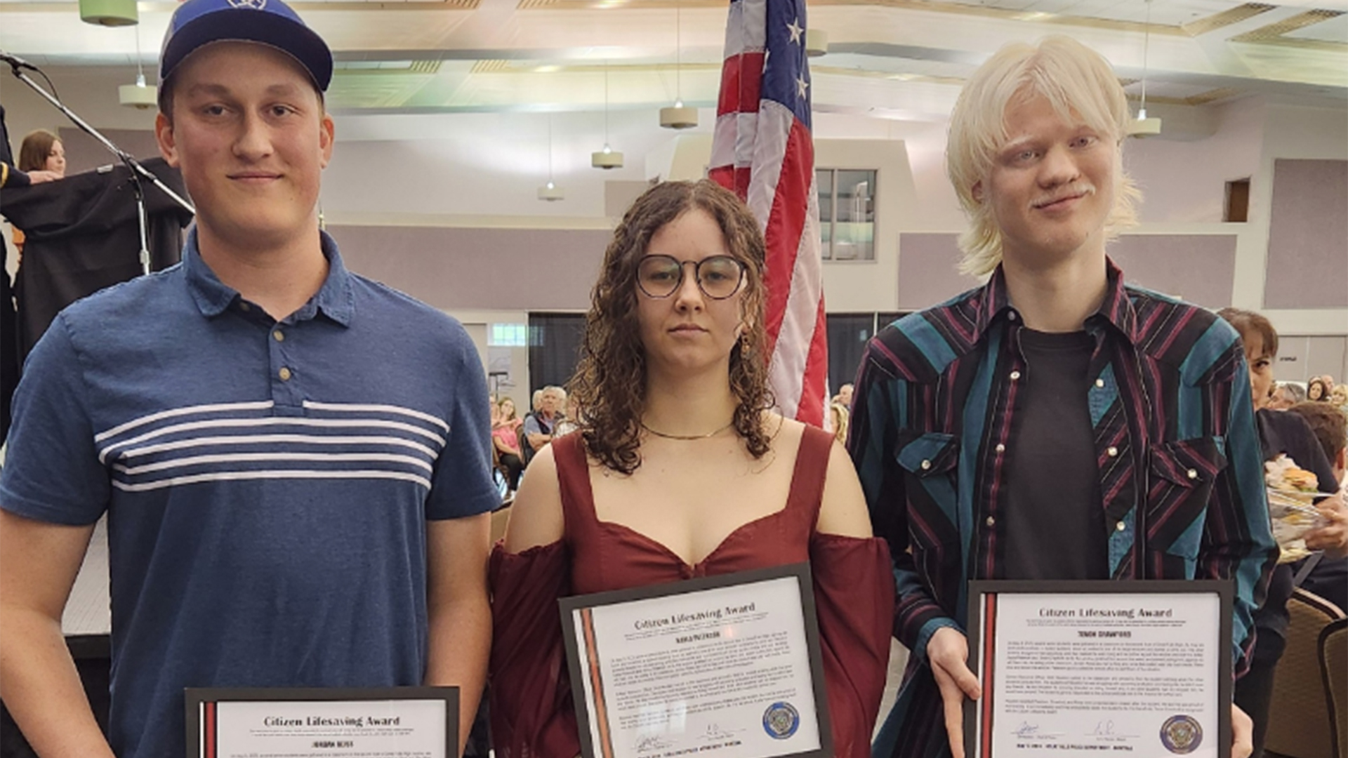 Three young adults holding certificates
