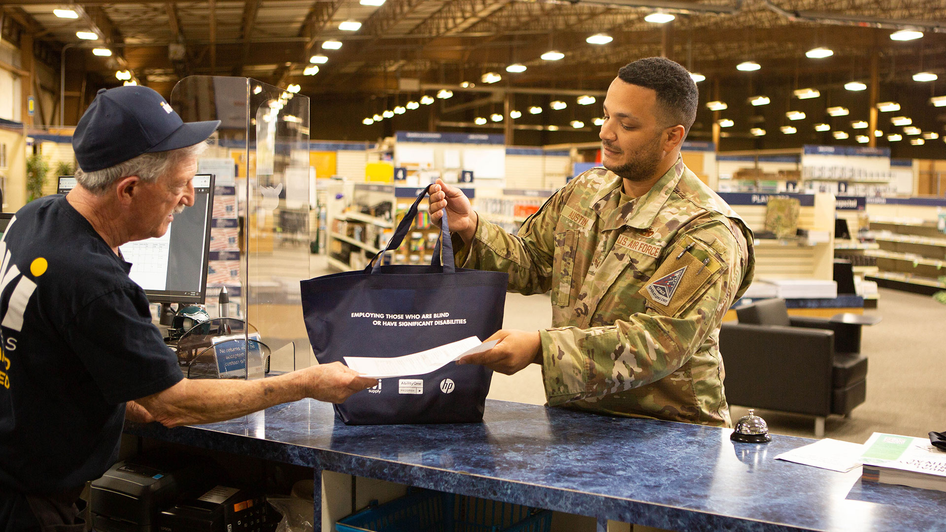 IBVI employee handing a bag of supplies to a man in a military uniform.