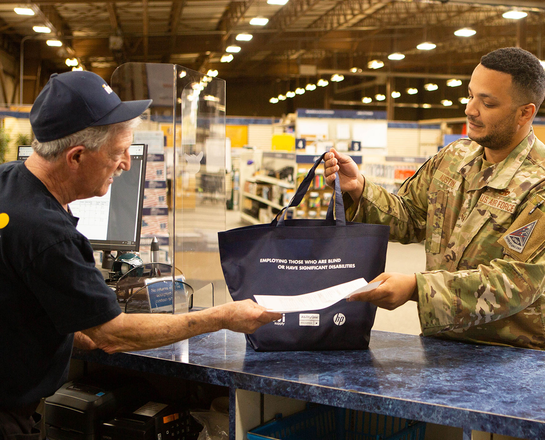 IBVI employee handing a bag of supplies to a man in a military uniform.